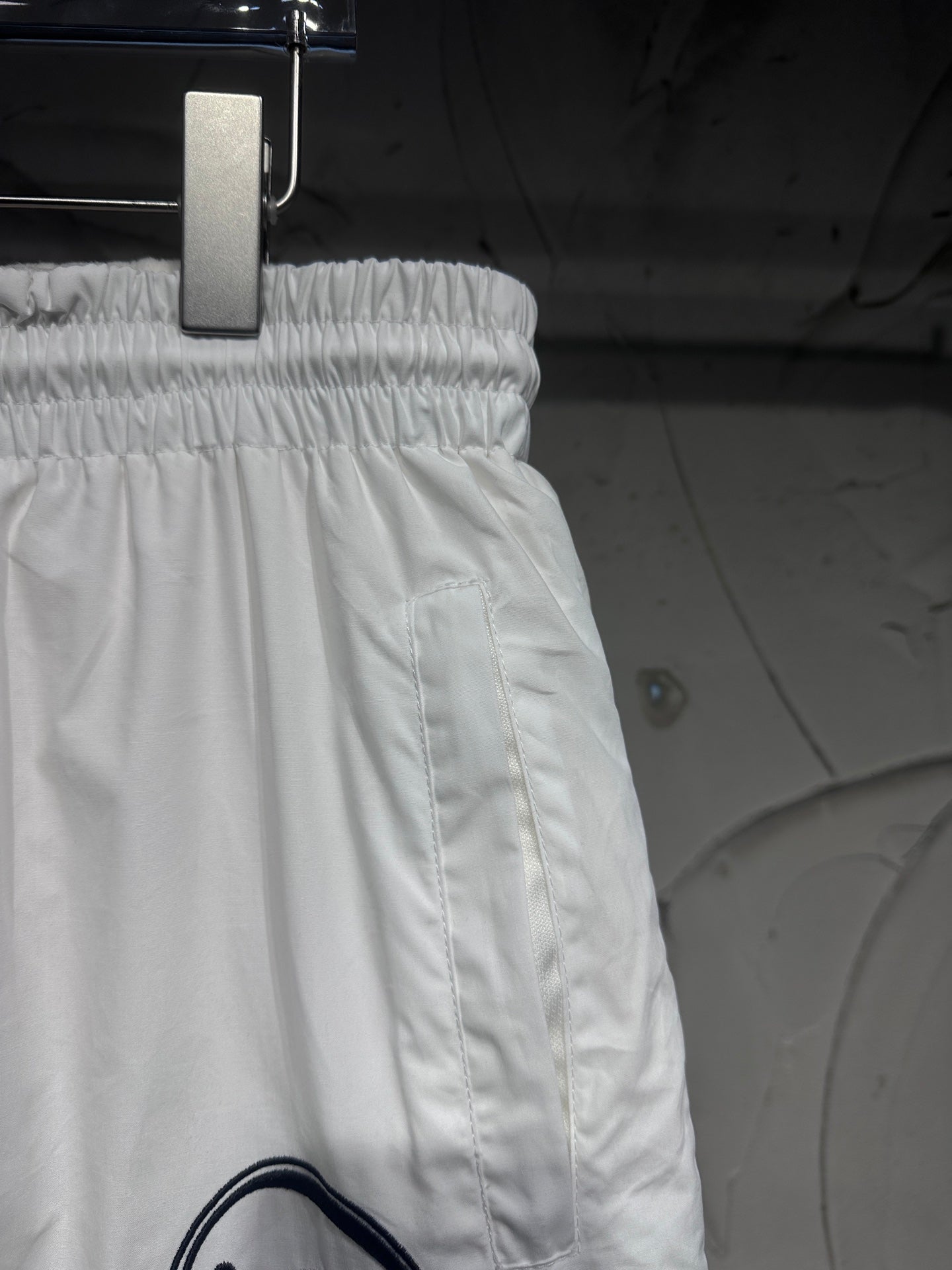 White track pants with elastic waistband and side seam stitching, relaxed fit