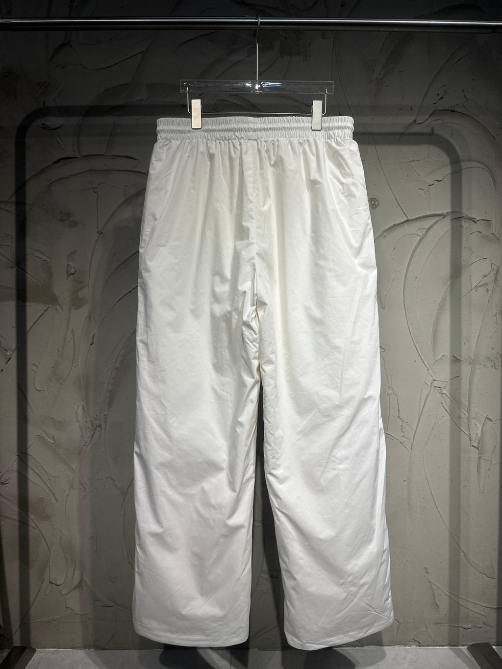 White track pants with elastic waistband and relaxed wide-leg silhouette