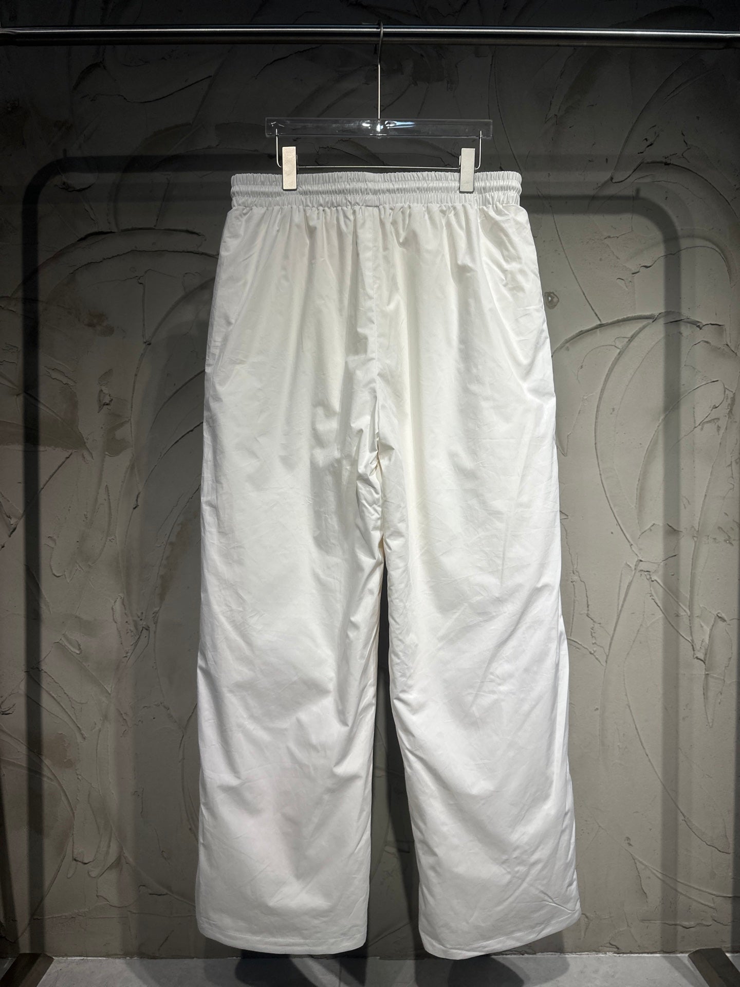 White track pants with elastic waistband and relaxed wide-leg silhouette