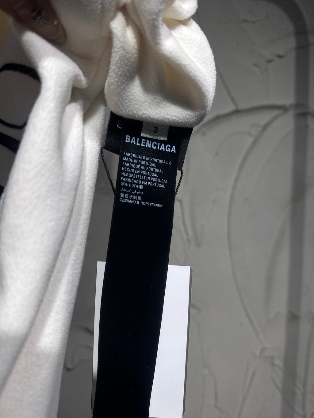 White pants care label inside waistband area; shows Balenciaga brand and sizing text