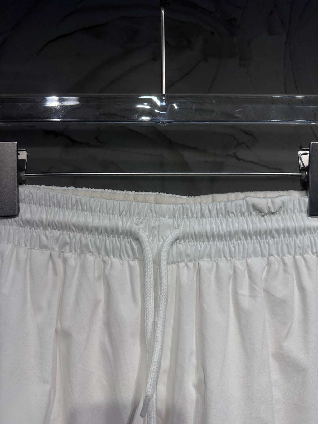 White elastic-waist track pants with drawstring and gathered cuffs at top