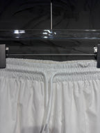 White elastic-waist track pants with drawstring and gathered cuffs at top