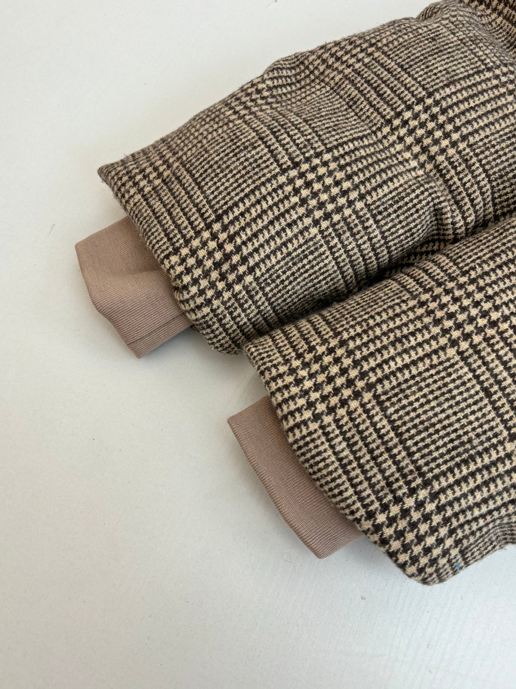 Houndstooth jacket laid flat with folded sleeves and light lining cuffs