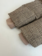 Houndstooth jacket laid flat with folded sleeves and light lining cuffs