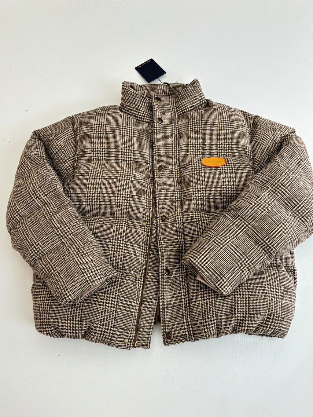 Houndstooth puffer jacket with stand collar, button placket, and orange chest patch