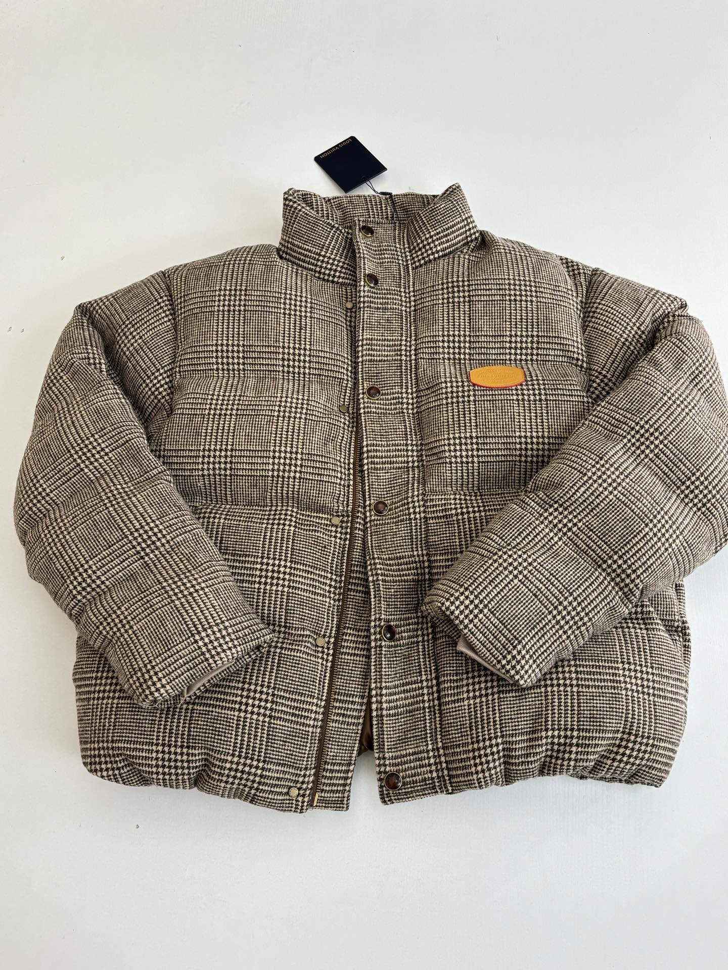 Houndstooth puffer jacket with stand collar, button placket, and orange chest patch