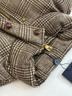 Houndstooth jacket close-up with zipper, snap buttons, and small logo tag