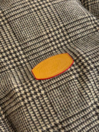 Close-up of houndstooth jacket fabric with orange Louis Vuitton logo patch