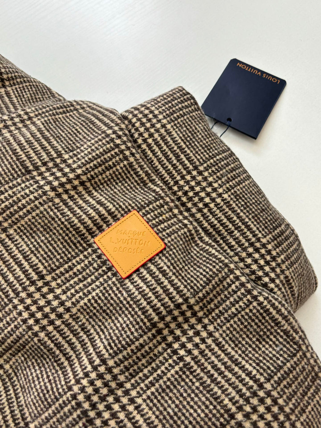 Houndstooth jacket collar with orange Louis Vuitton logo patch and blue tag