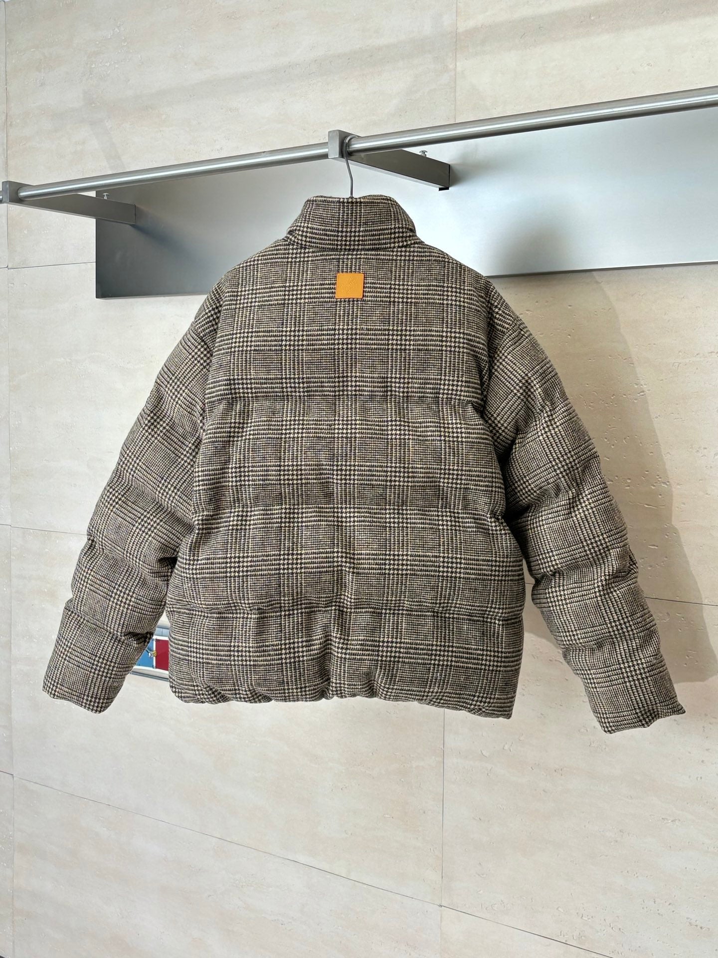 Back view of houndstooth puffer jacket with stand collar and yellow logo patch