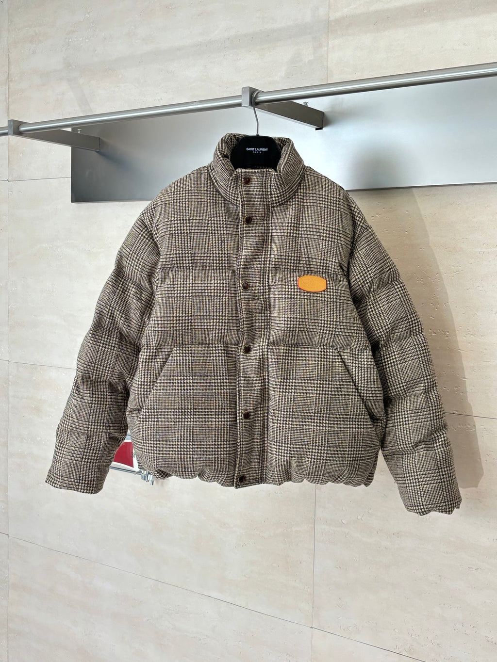 Houndstooth puffer jacket with button front, stand collar, and orange logo patch