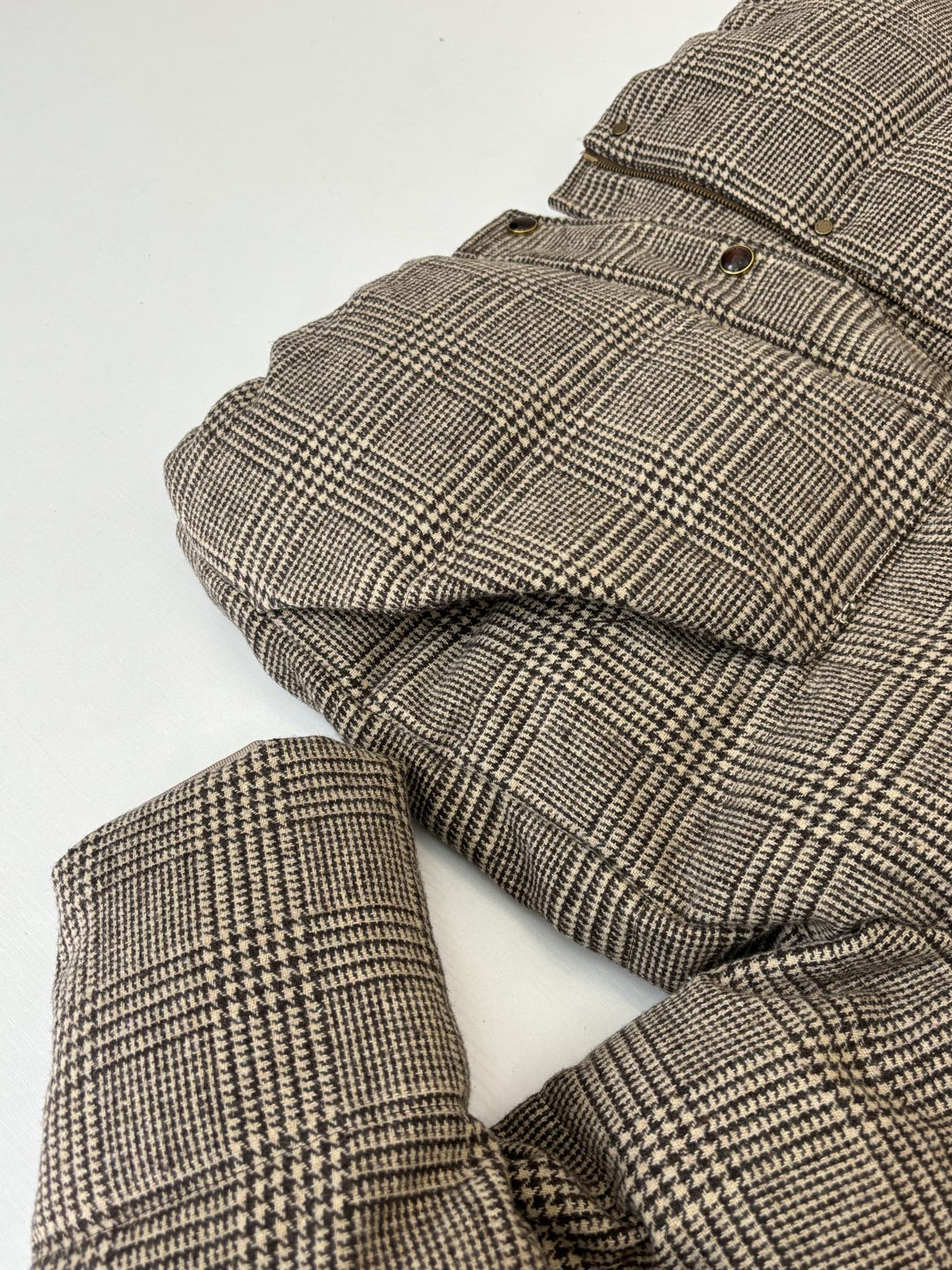 Houndstooth puffer jacket with quilted sleeves and cuffs laid flat for viewing