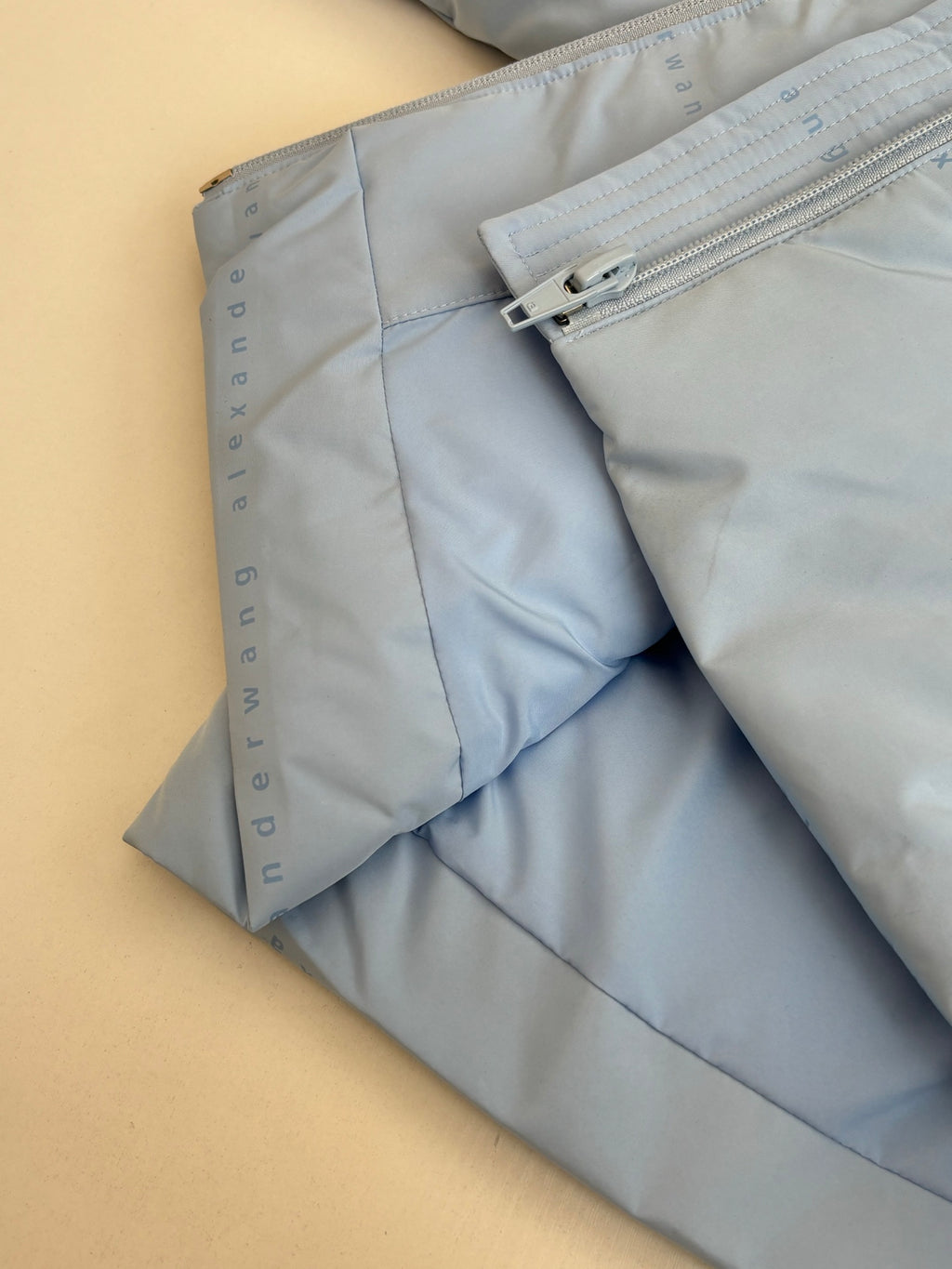 Light blue puffer jacket side with zipper opening and seam stitching