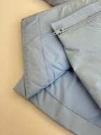 Light blue puffer jacket side with zipper opening and seam stitching