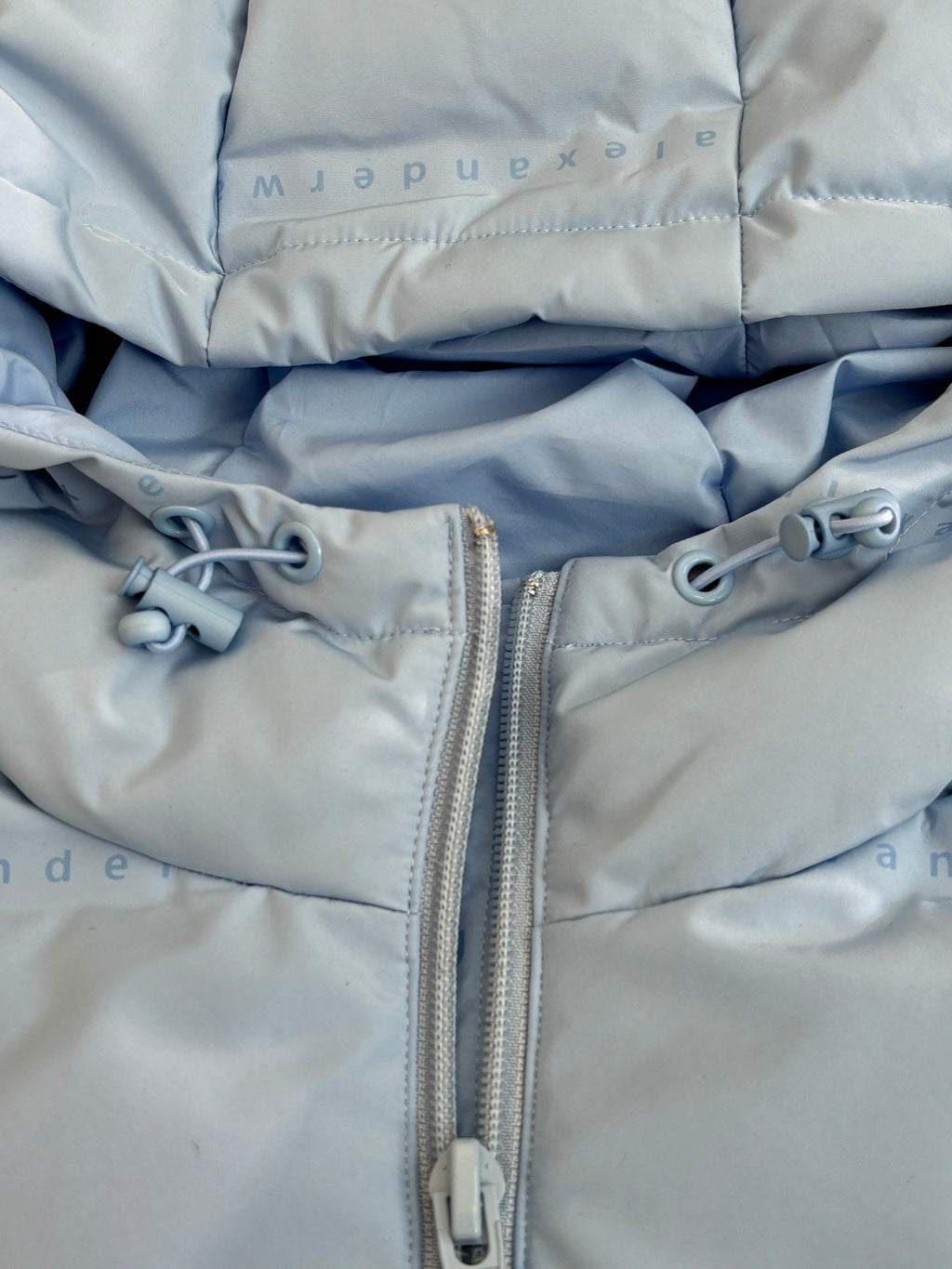 Light blue puffer jacket front zipper with metal pull and toggles