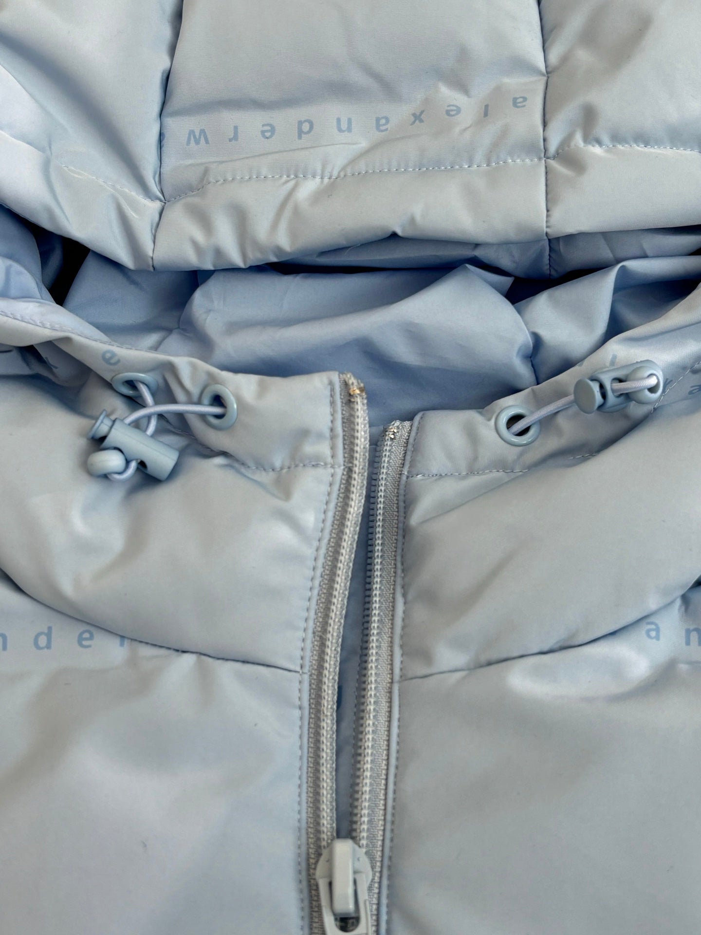 Light blue puffer jacket front zipper with metal pull and toggles