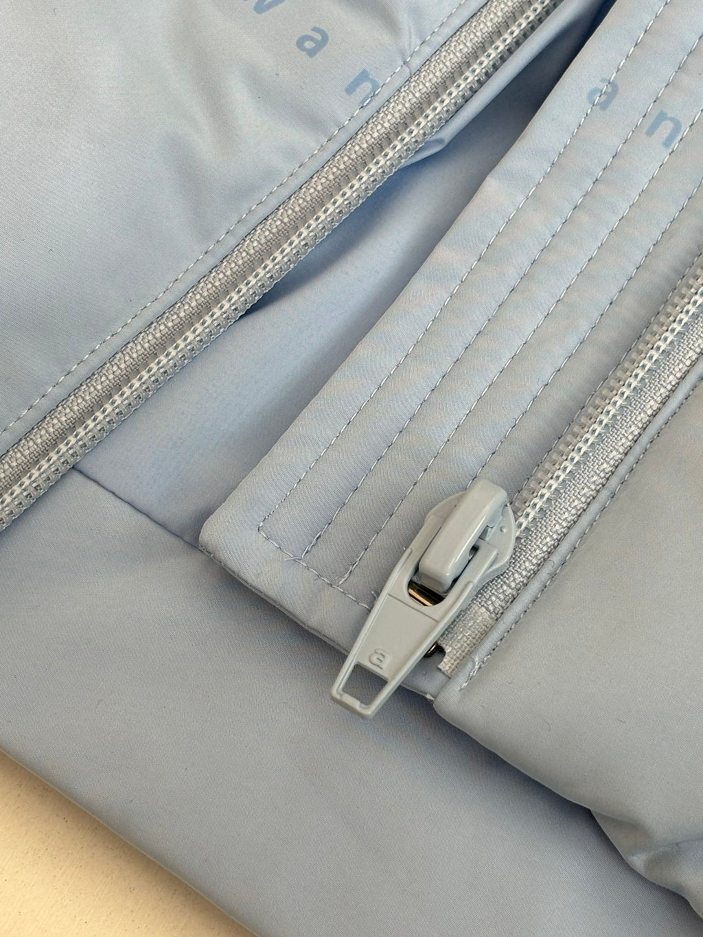 Light blue puffer jacket cuff with zipper and snap tab