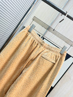 Beige dotted pants with elastic waist and relaxed drape, full-length view
