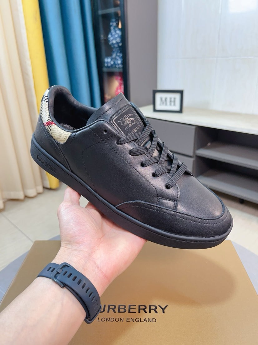 Leather low-top sneaker in dark blue held in hand, lace-up front and side patch