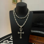 Silver-tone cross pendant necklace with layered textured chain and ring clasp.