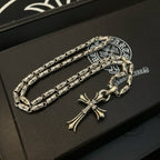 Silver-tone cross pendant necklace with textured link chain and small clasp detail.