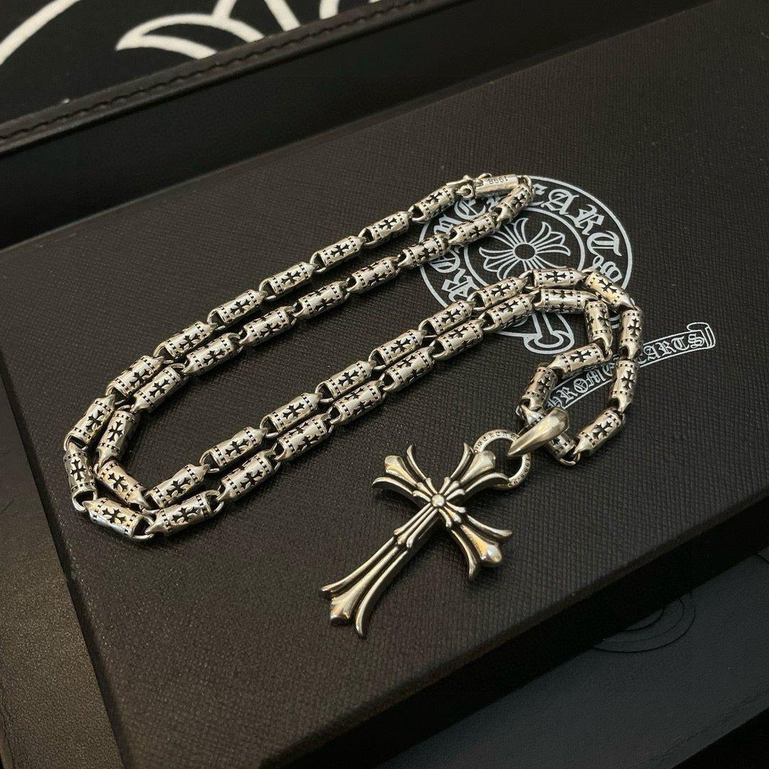 Silver-tone cross pendant necklace with textured link chain and small clasp detail.