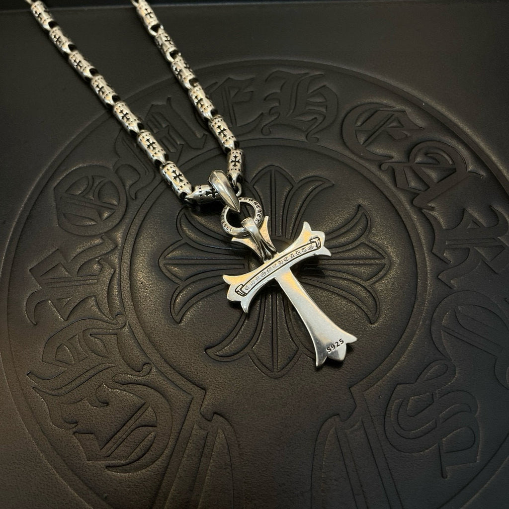 Silver-tone cross pendant with textured link chain, close-up view.