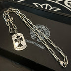 Silver charm necklace on tray with dog-tag pendant and compass-style charm