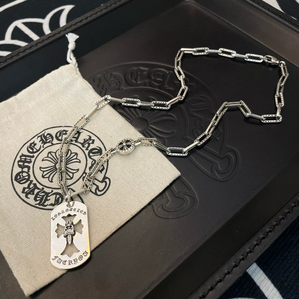 Silver chain necklace with circular pendant and cross charm on jewelry tray