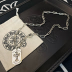 Silver chain necklace with circular pendant and cross charm on jewelry tray