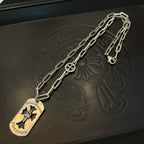 Silver chain necklace laid on leather with circular pendant and flower emblem charm