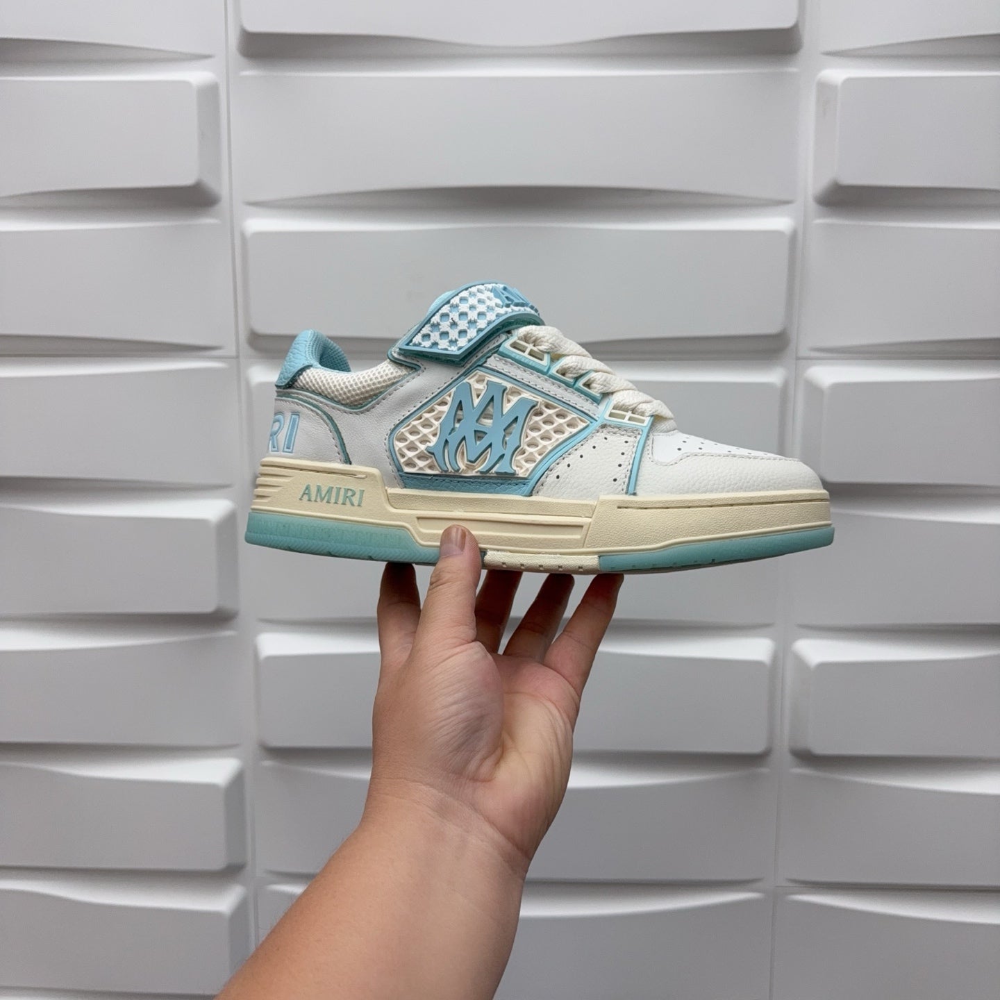 Amiri low-top sneakers, side profile; white upper with light blue trim and logo