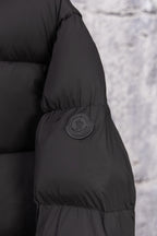 Dark puffer coat sleeve with round logo patch and quilted paneling