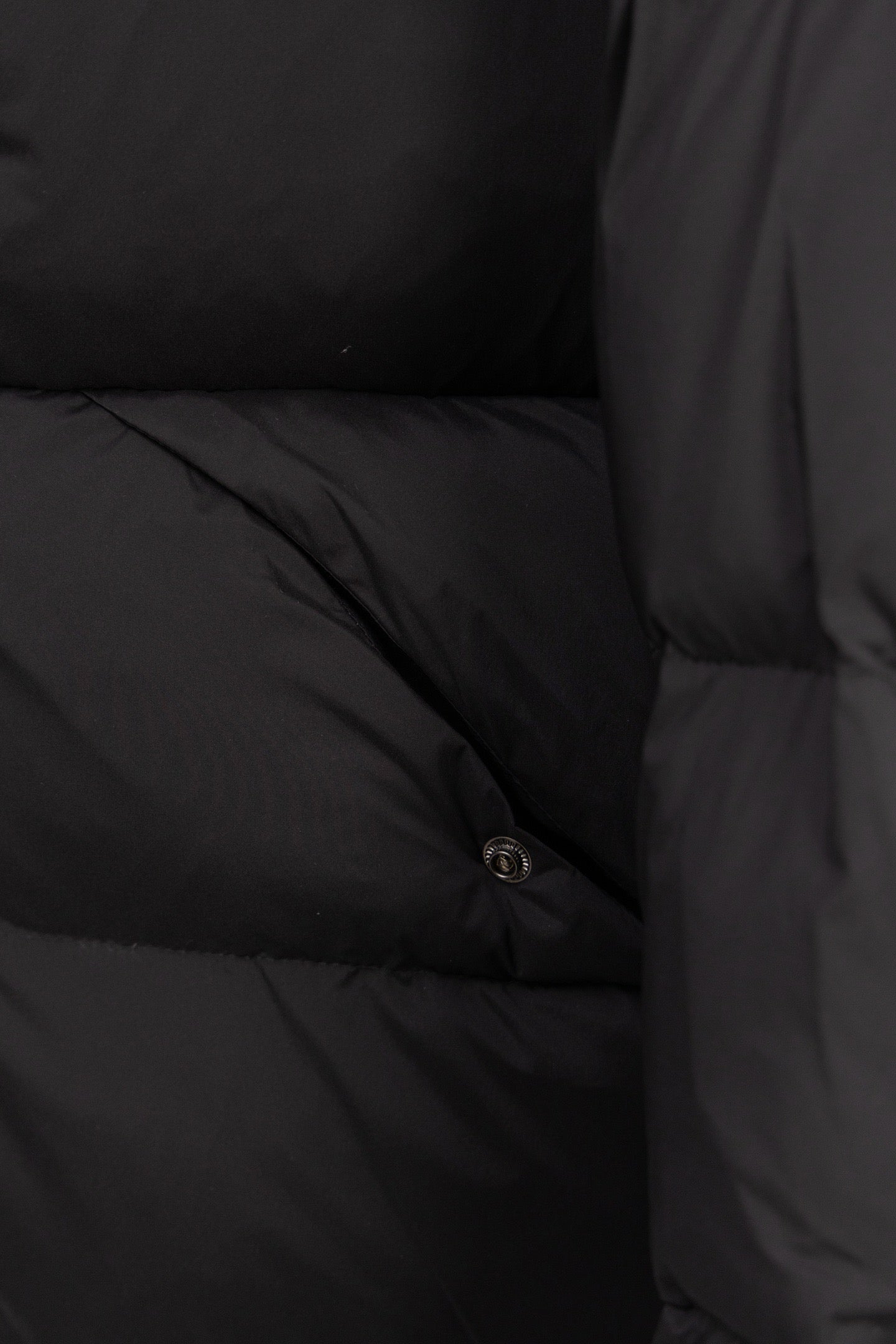 Dark puffer coat lining with stitched quilted sections and small snap button