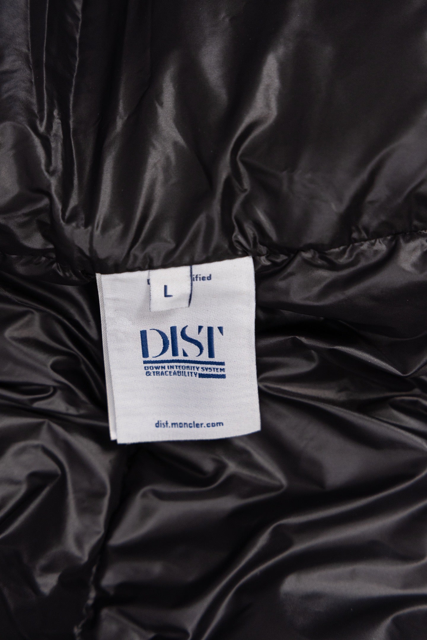 Size label on dark puffer coat: L and 'DISTI' printed
