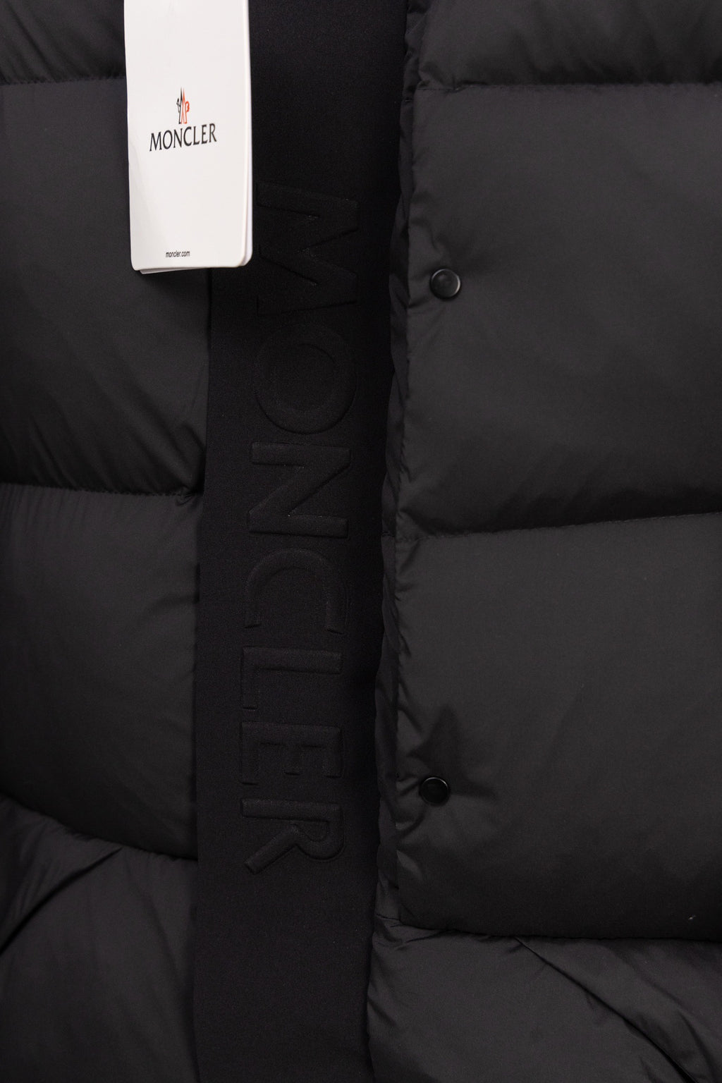 Dark puffer coat with vertical MONCLER lettering strip and front snap buttons
