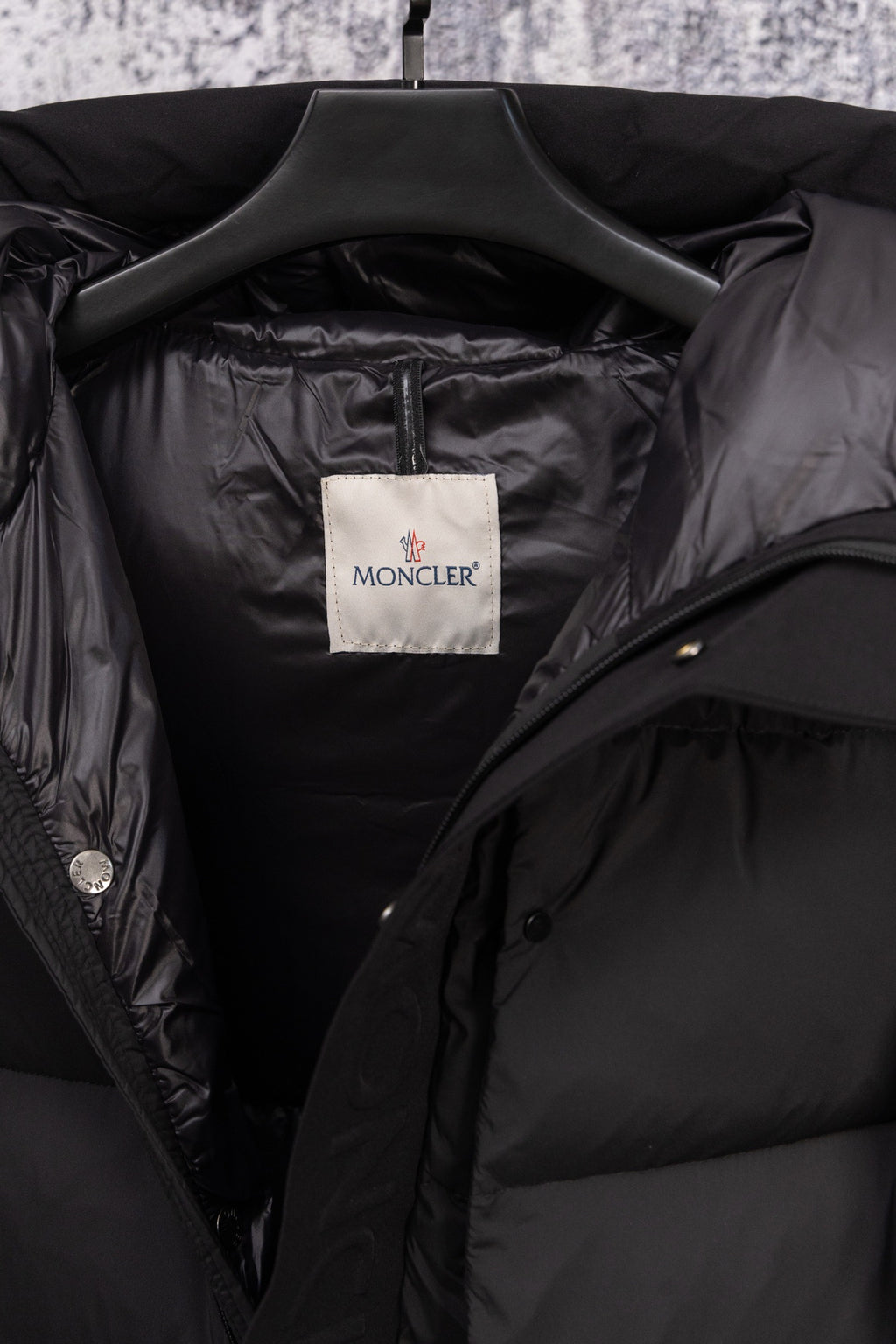 Dark puffer coat interior with Moncler label and open collar lining