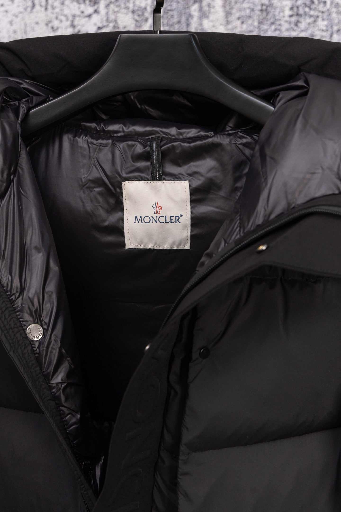 Dark puffer coat interior with Moncler label and open collar lining