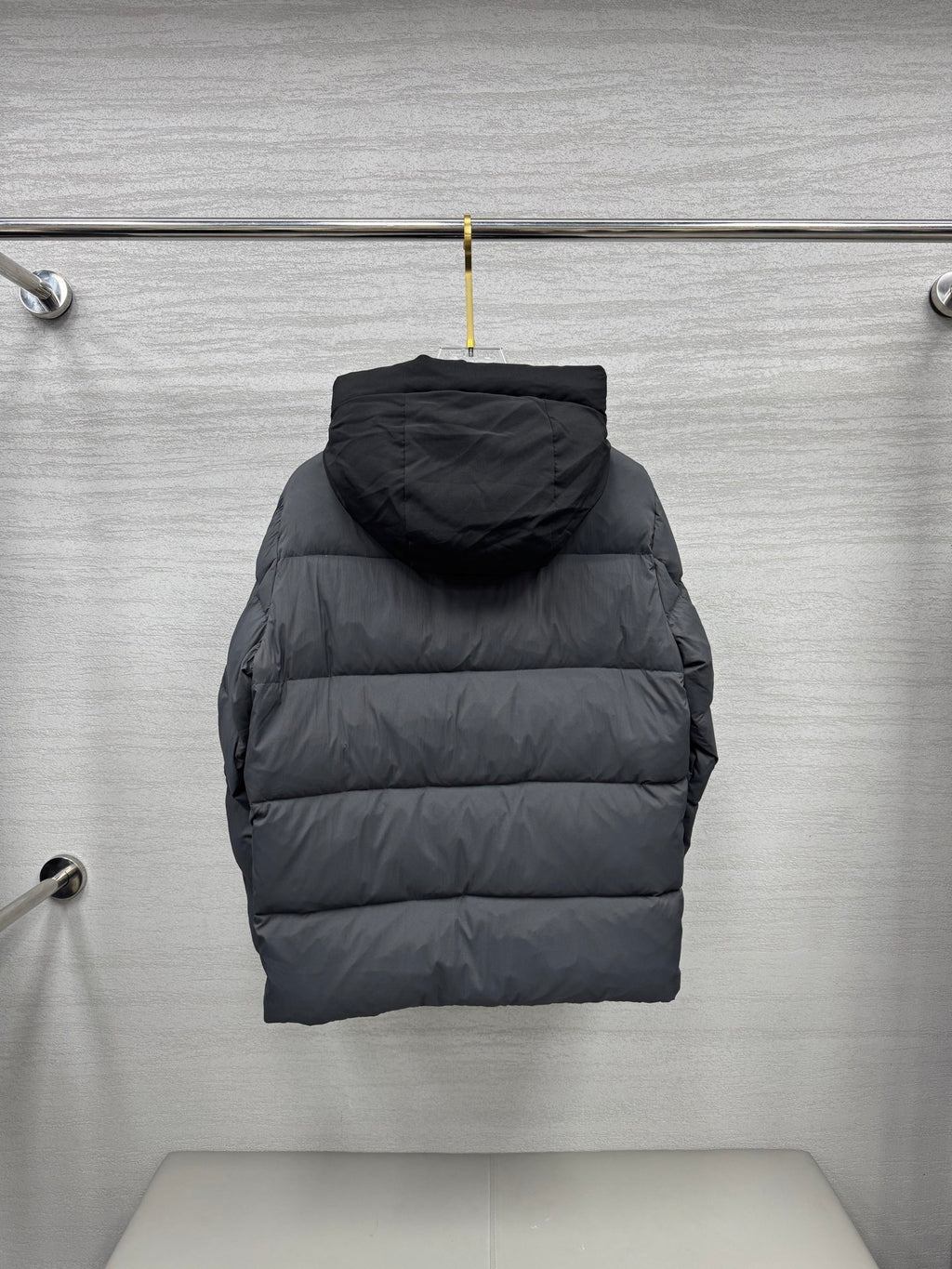 Long hooded puffer jacket, back view, dark gray quilted construction