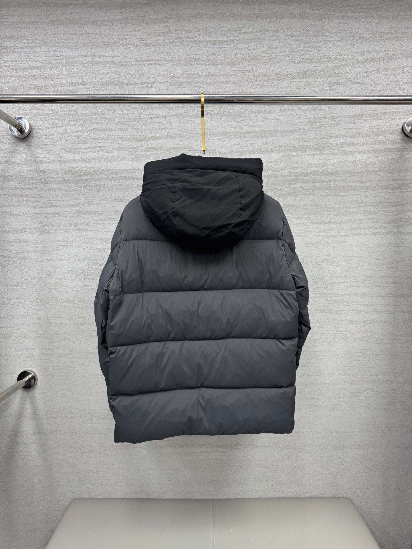 Long hooded puffer jacket, back view, dark gray quilted construction