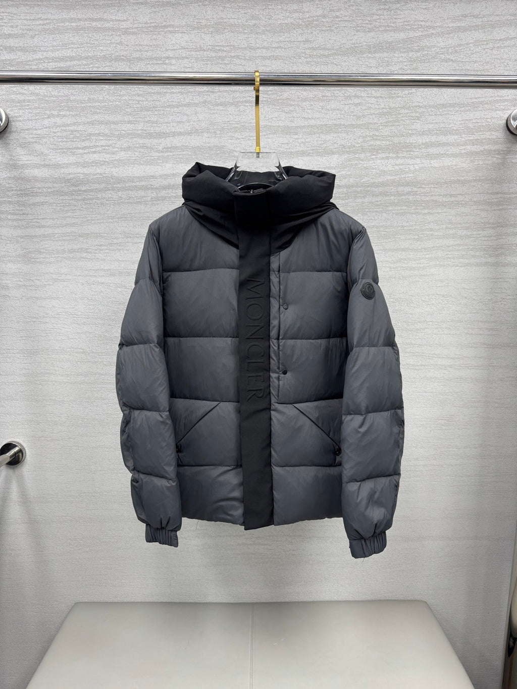 Moncler hooded puffer jacket, dark gray front on hanger with quilted panels