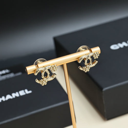 Chanel hoop earrings with gold-tone accents and dark blue stones, on display stand