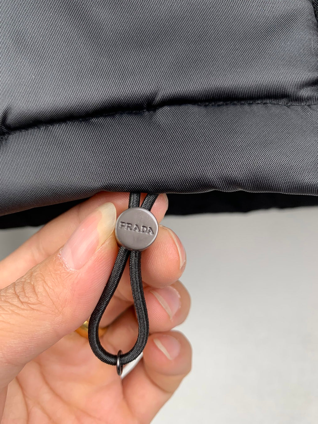 Black drawstring cord with PRADA round cap and looped elastic knot