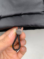 Black drawstring cord with PRADA round cap and looped elastic knot