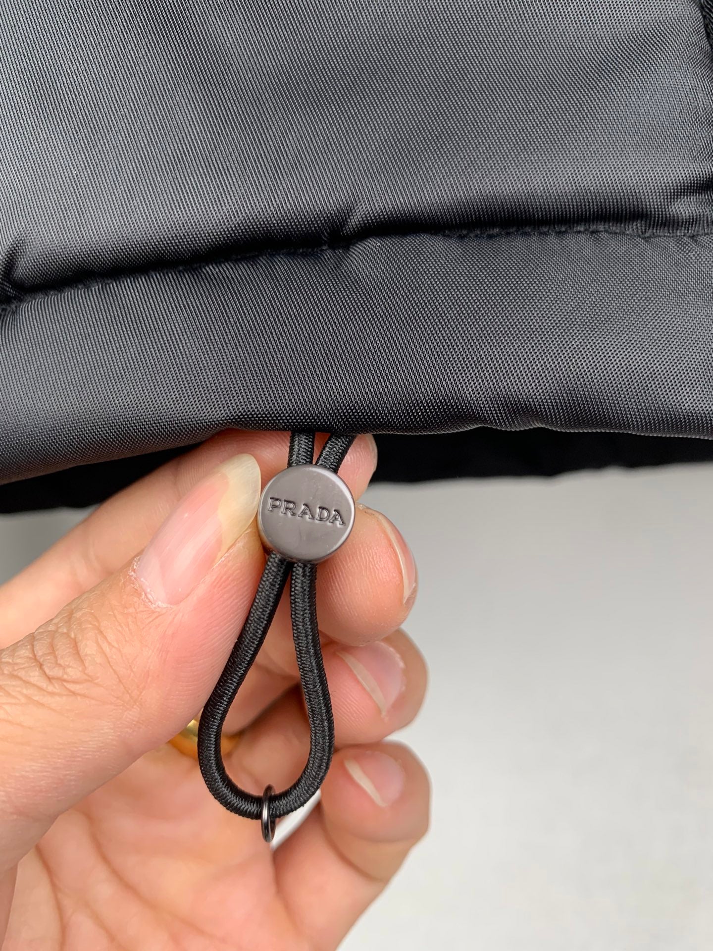 Black drawstring cord with PRADA round cap and looped elastic knot
