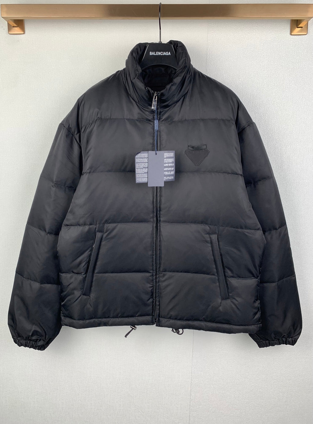 Dark puffer jacket with full-zip front, stand collar, and chest logo patch