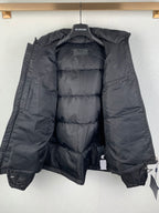 Dark puffer jacket with lining exposed, front zipper area, and adjustable cords