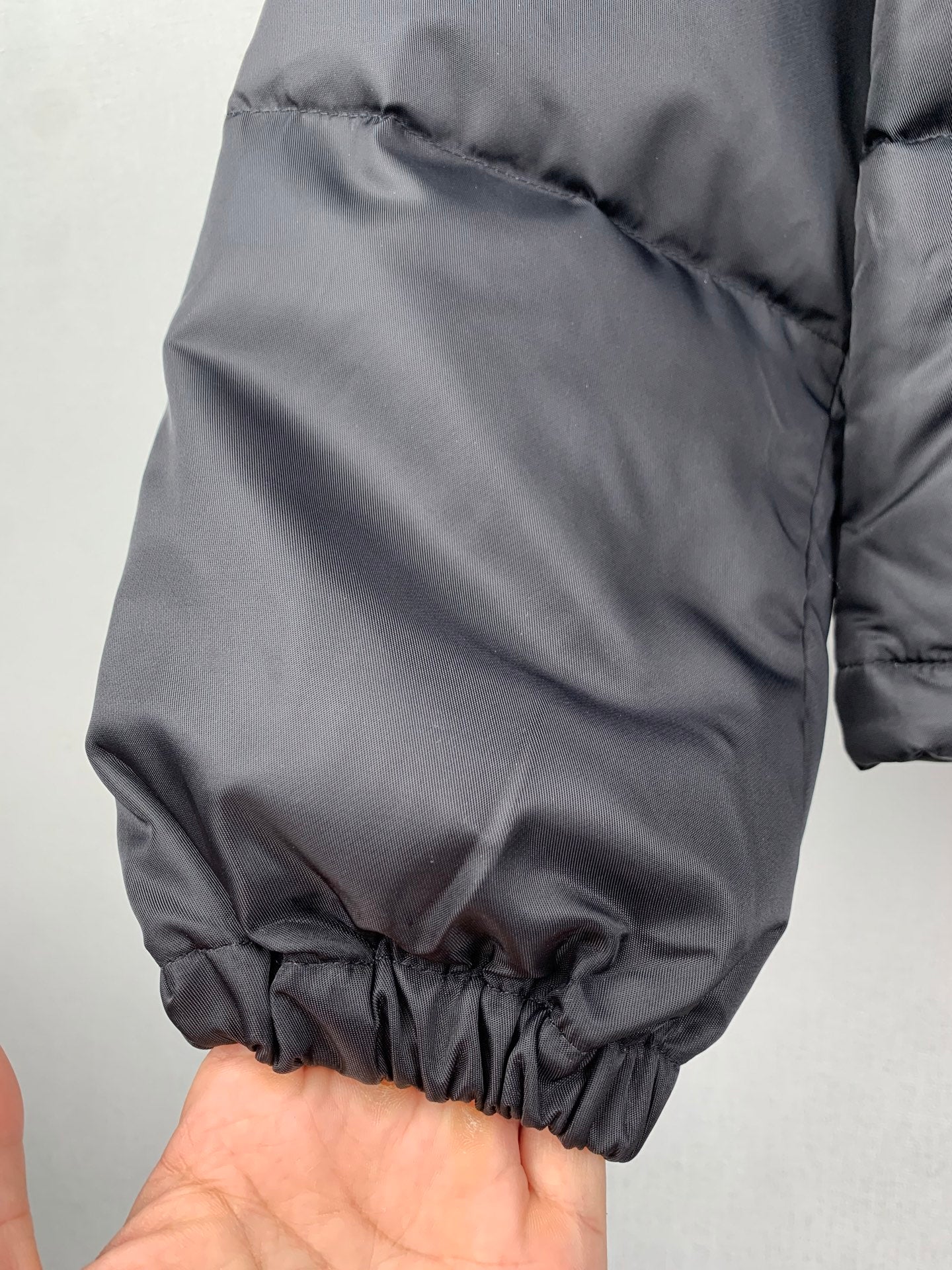 Gray puffer jacket sleeve cuff area with elastic hem and gathered fabric