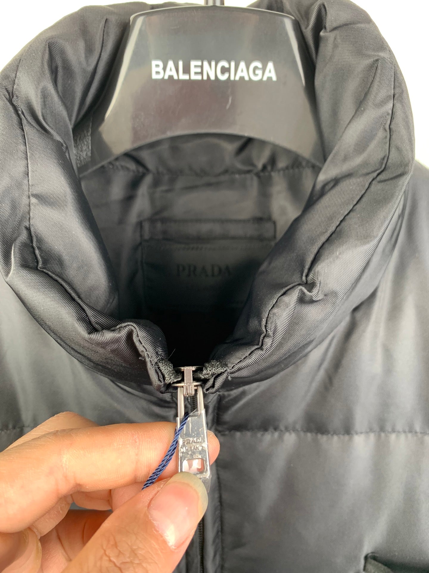 Gray puffer jacket interior hood with metal zipper pull and PRADA logo tag