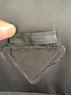 Gray fabric label with stitched triangular emblem and PRADA text